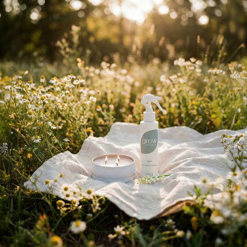 Linen spray and candle on a cotton cloth in a field of flowers