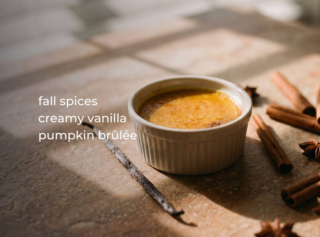 A small white ramekin filled with pumpkin brûlée sits on a stone surface with cinnamon sticks, star anise, and a vanilla bean around it. White text on the left reads 'fall spices creamy vanilla pumpkin brûlée'. (featured)