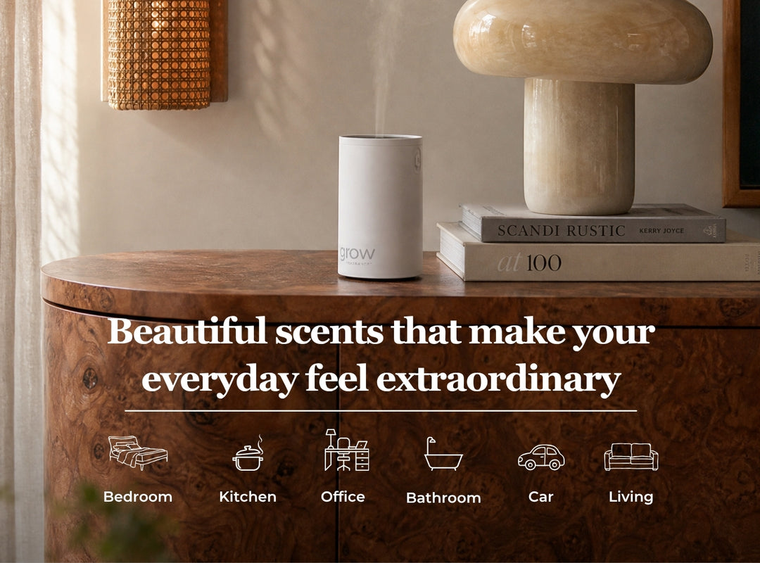 A white cylindrical smart diffuser sits on a wooden cabinet in a styled interior setting with a mushroom lamp and books. Large text reads 'Beautiful scents that make your everyday feel extraordinary,' with smaller icons below indicating use cases: bedroom, kitchen, office, bathroom, car, and living. (featured)