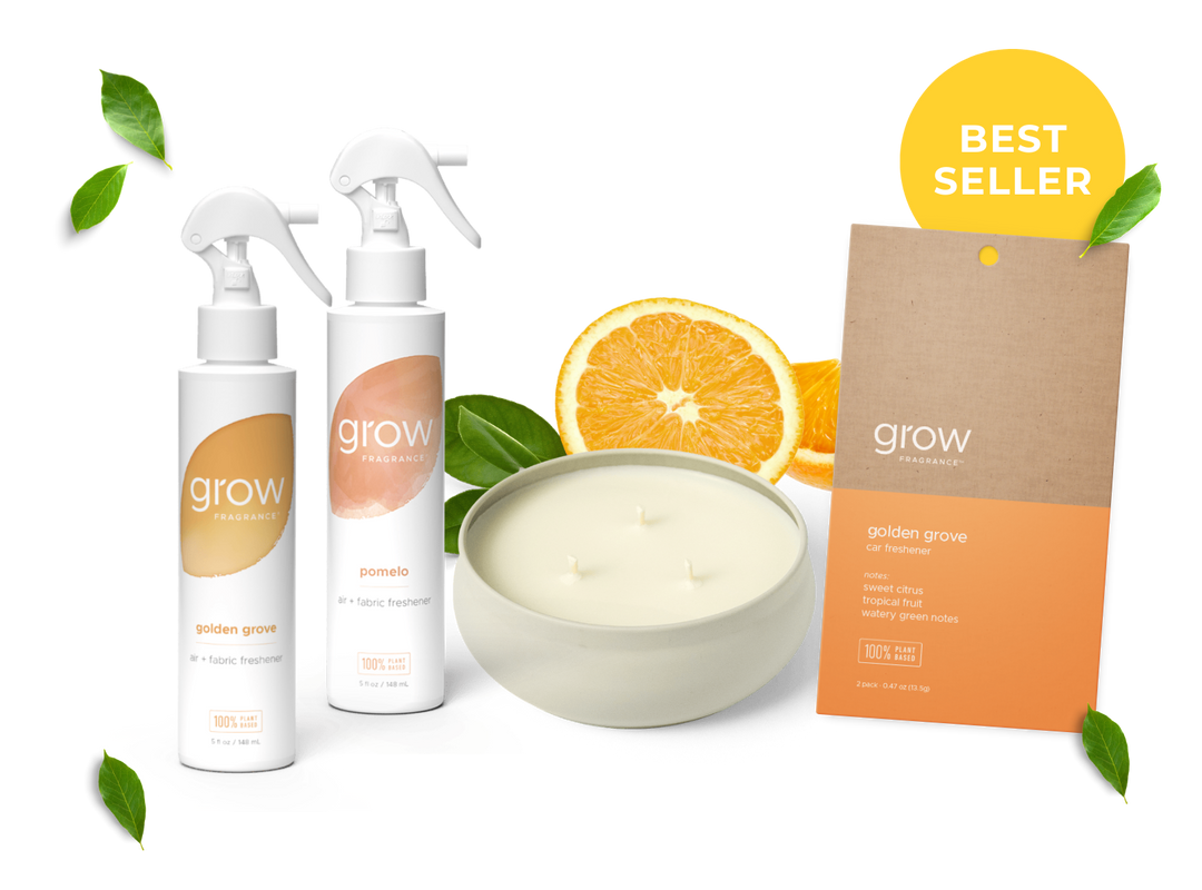 Grow skincare products including bottles, 3 wick candle, and a box on a white background with orange slices and leaves.