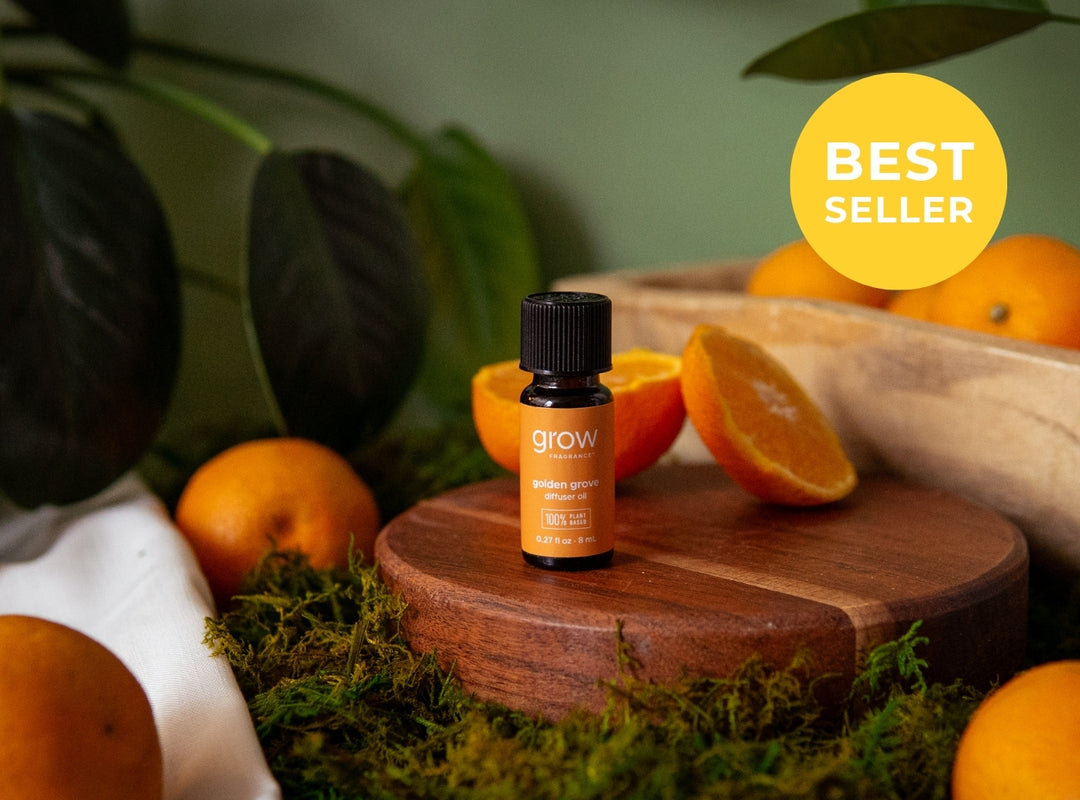 A small amber essential oil bottle labeled 'grow' stands on a round wooden pedestal surrounded by oranges, moss, and green leaves. A yellow circular badge in the top right reads 'BEST SELLER'. (featured)
