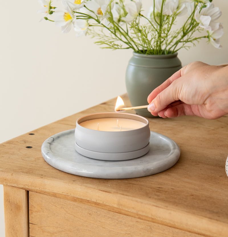 Hand with lit match lighting a Grow Fragrance non toxic 3 wick candle