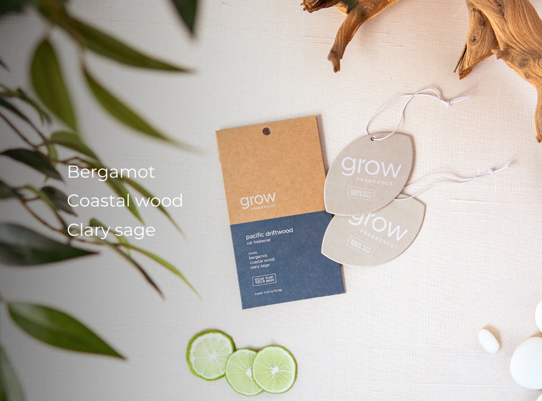 Scented diffuser tags with 'grow' branding on a white surface with green leaves. Scent notes: bergamot, coastal wood, clary sage