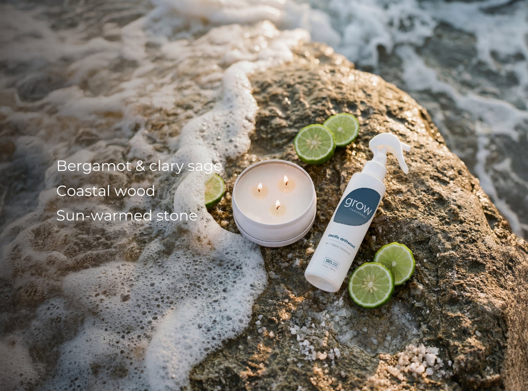 Candle, bottle, and lime slices on a rock with ocean waves in the background