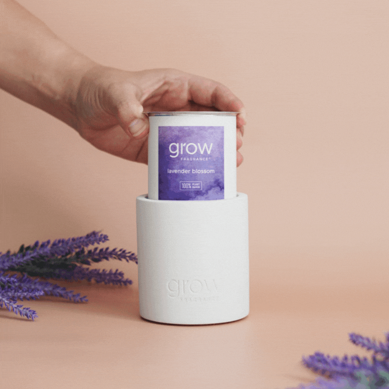 Hand holding a Grow Fragrance candle labeled Lavender Blossom placing in candle holder