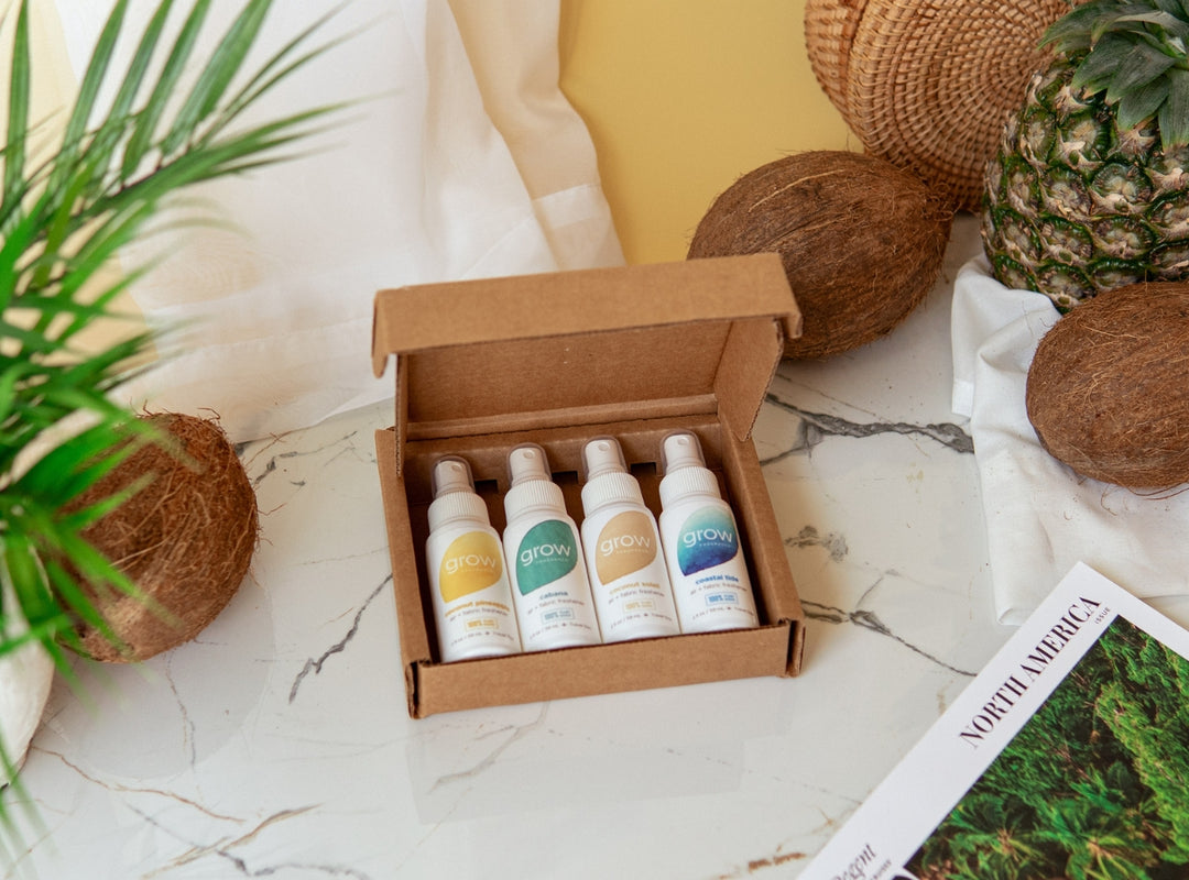 Box of 2 oz Grow Fragrance sampler bottles on a marble surface with coconuts and a plant.