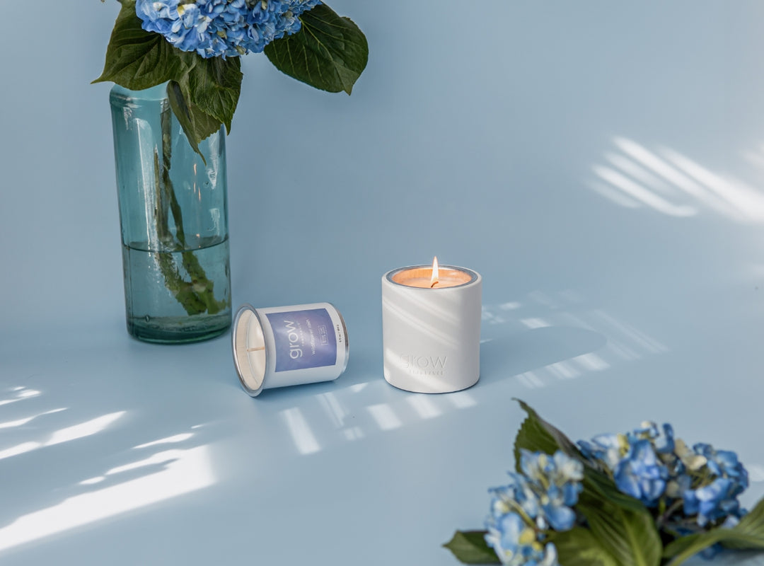Wildflower Rain Candle on blue background with natural light and blue flowers (featured)