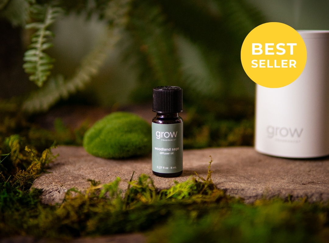 A small dark glass bottle labeled 'grow' with a black cap stands on a stone surface surrounded by moss and greenery. A large white cylindrical container is partially visible behind it, and a yellow circular badge in the top right reads 'BEST SELLER'. (featured)