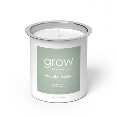 Candle in a white container with a green 'woodland sage' label on a white background