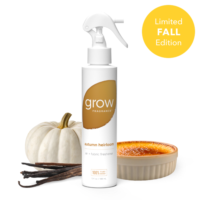 A white spray bottle of Grow Fragrance 'Autumn Heirloom' fabric and air freshener, styled with a small white pumpkin, vanilla beans, and a caramel dessert on a white background with a yellow 'Limited Fall Edition' badge.