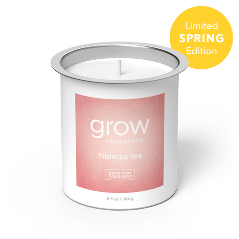 Candle in a white container with a pink 'hibiscus tea' label on a white background