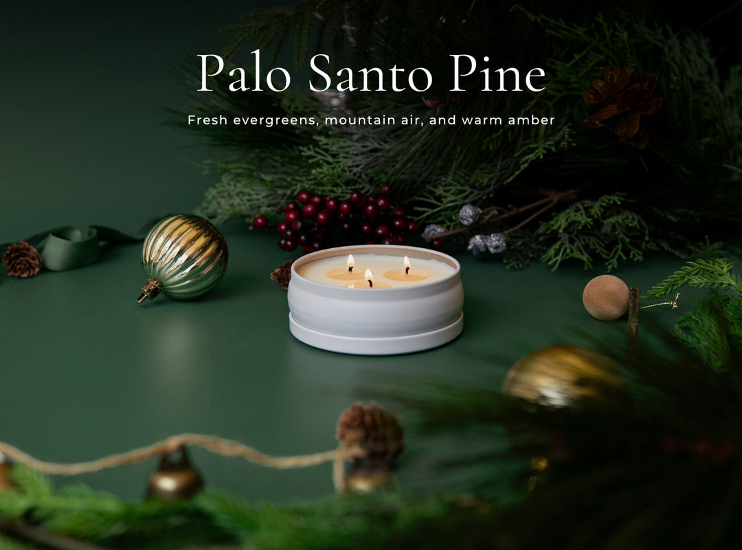 Candle with greenery and decorative elements on a dark background, featuring 'Palo Santo Pine' text.
