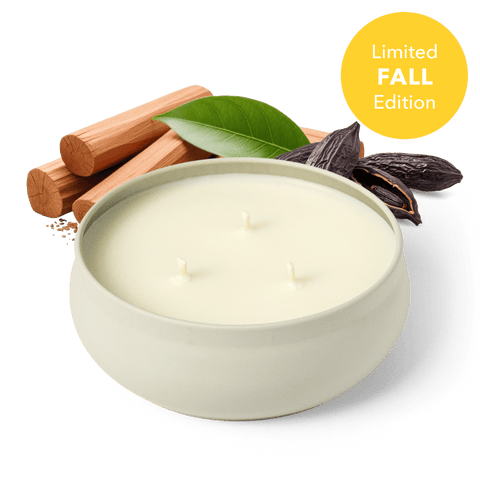 A white three-wick candle in a round white vessel, styled with cinnamon sticks, a green leaf, and dark cacao beans on a dark green background, with a yellow 'Limited FALL Edition' badge in the top right.