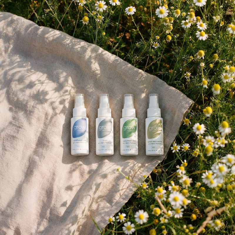 4 Grow Fragrance air and fabric 2 oz spray bottles on a stone surface with flowers in the background